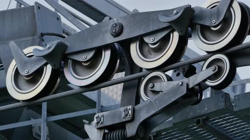 Closeup of a Ski Lift Mechanism with Spinning Pulley Wheels on a Steel Cable