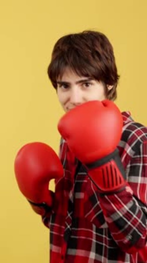 Young Adult Boxing in Red Gloves on Yellow Background