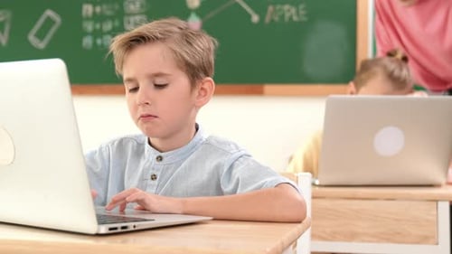 Smart boy working at laptop while diverse children programing system. Pedagogy.