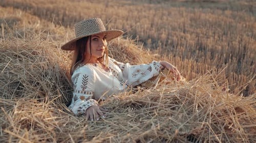 Woman Lies in Hay Field at Sunset
