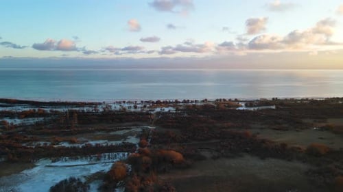 Vista aérea del paisaje del atardecer en la costa del lago Issyk-Kul con nubes