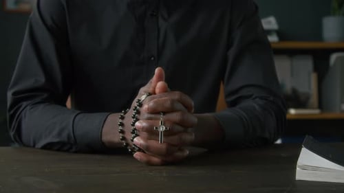 Person Praying with Rosary Beads and Cross