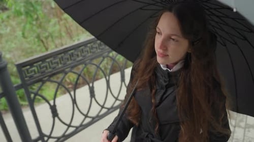 Girl With Umbrella Standing on a Bridge on Cloudy Day