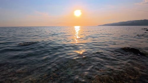 beautiful sunset on the sea, waves, and pebble beach. Slow motion