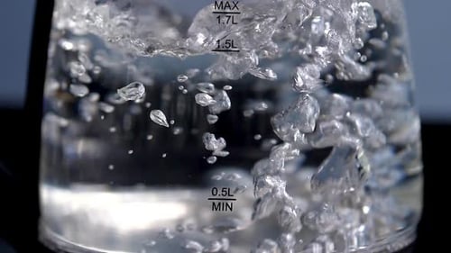Rapid boiling water in a clear glass kettle, slow motion, close up
