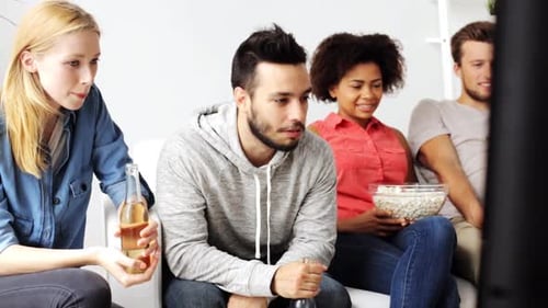 Friends laughing and watching television on couch