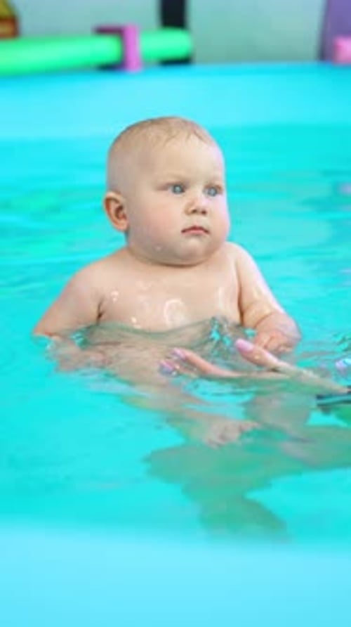 Beautiful blond baby is in the swimming pool.