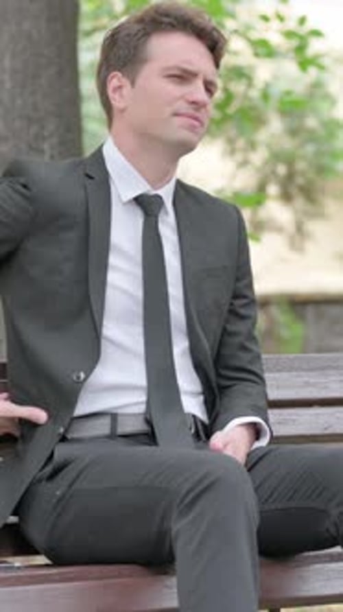 Man in Suit Sitting on Bench Outside