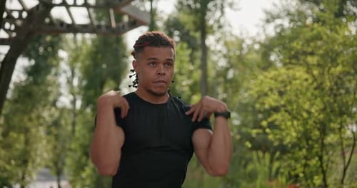 Man Stretching Shoulders in Park Before Outdoor Workout