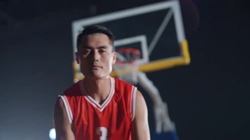Basketballspieler schlägt den Ball auf den Boden, wärmt sich vor dem Spiel auf Asiatischer Basketballspieler