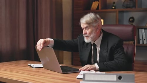 Aged Employee Activating Portable Computer at Office Desk