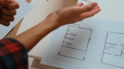Architect Studying Building Plans with Model Home