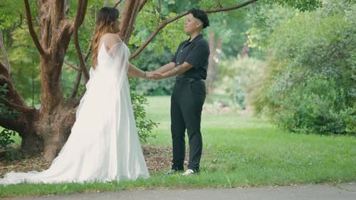 Happy Lesbian Latina Couple Holding Hands in Love on Wedding Day. Outdoor Summer Wedding with Green