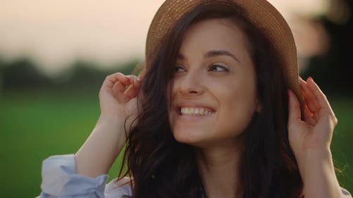 Smiling woman wearing hat in golden sunlight