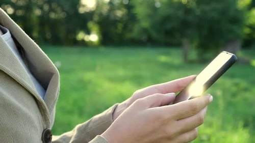 Closeup of Female Hands Using a Smart Phone Nature Background Woman Using Mobile Phone in Sunset