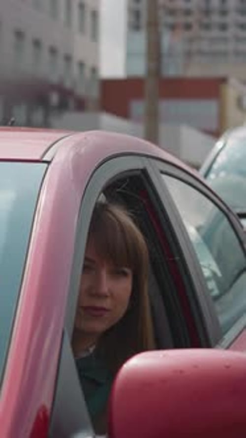 Curious Woman Looks Out of Red Car Window to Examine Road