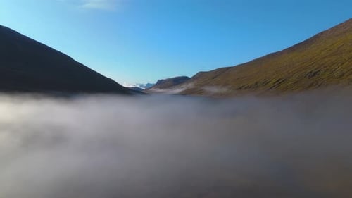 Aerial establishing shot overhead low-lying clouds in an Icelandic valley