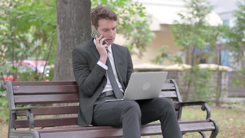 Young Adult Working on Laptop Talking on Phone
