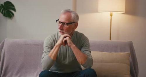 Senior Man Sitting Thoughtfully on Couch Indoors