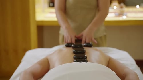 Asian Spa Wellness Center Masseuse Makes Hot Stones Massage to Client Back and Neck Woman Performs