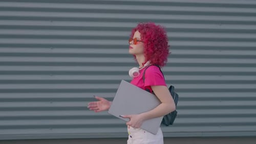 A Pink Curly Woman is Walking to Work or College Casual Freelancer Outdoors Coffe Break Education