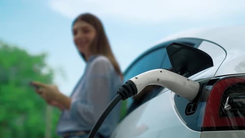 Frau bezahlt mit Smartphone für das Aufladen von Elektroautos. Erheben