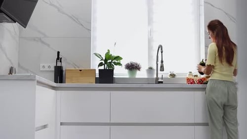 Una joven saca verduras y frutas orgánicas de una bolsa reutilizable en la cocina moderna