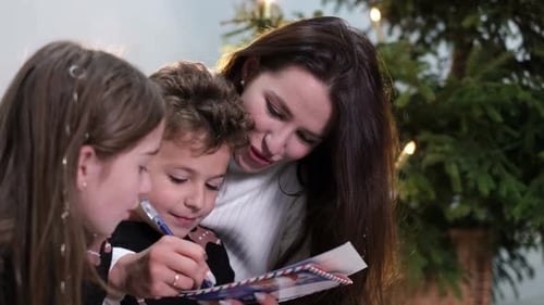 Family Writes Christmas Letter Together by the Tree