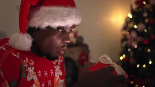 Man Receiving a Christmas Gift by a Christmas Tree