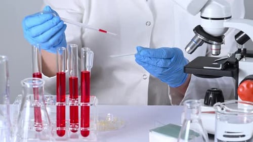 Scientist uses Pipette in Laboratory with Microscope