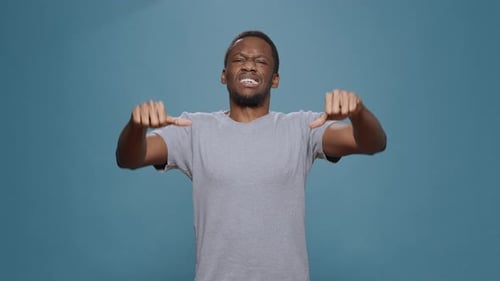 Disappointed Person Showing Thumbs Down Symbol in Studio