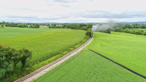 Uma vista aérea das terras agrícolas Amish com uma única ferrovia e uma aproximação de trem de passageiros a vapor