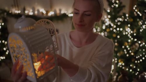 Woman Inserts Candle Into Lantern for Christmas Decor