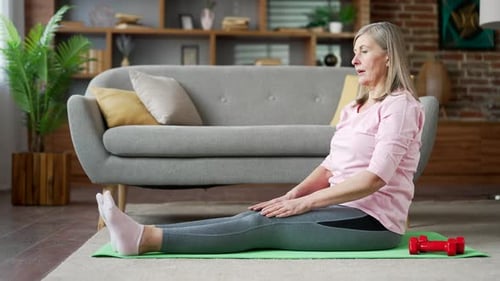 Attractive Senior Woman Stretching on Exercise Mat