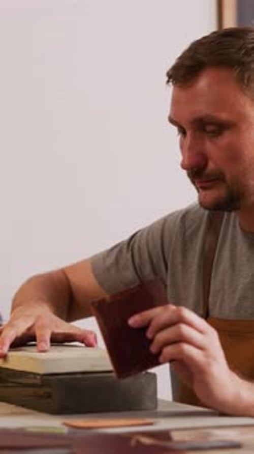 Bearded Worker Prepares Leather Sheet for Processing in Shop