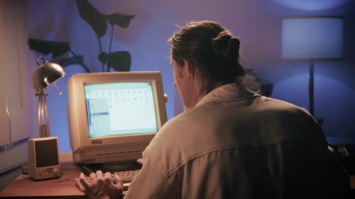 Человек, работающий и играющий на компьютере в стиле ретро, ИТ-инженер с винтажным компьютером дома, используя старый