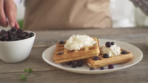 Decorating Waffles with Whipped Cream and Black Currants