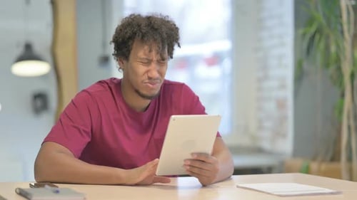 Young Adult at Desk Frustrated with Tablet