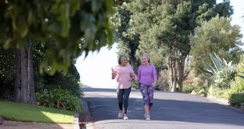 Multiracial female friends walking and talking on suburban street, outdoor exercise, copy space