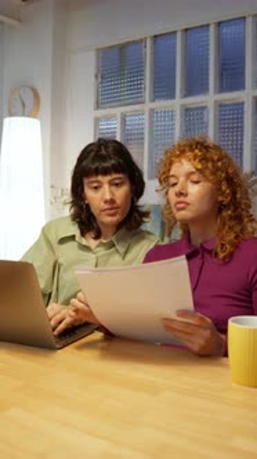 Lesbian Couple Reviewing Documents on Laptop in Slow Motion