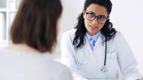 Medicine, Healthcare And People Concept - Doctor Talking To Woman Patient At Hospital