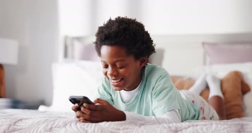 Happy Child Lying on Bed Using Smartphone