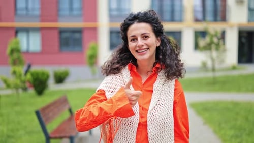 Happy Woman Showing Thumbs Up in a City Park