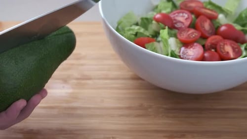 Cutting large ripe avocado in half for salad.