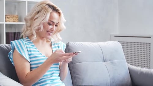 Young and Attractive Woman Works at Home Using Smartphone Freelancer or Student is Typing Message