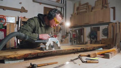 Man Cutting Wood With Saw in Workshop