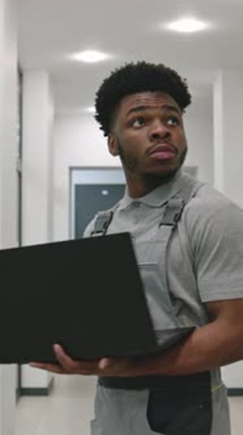 Young Adult Working with a Laptop in a Hallway