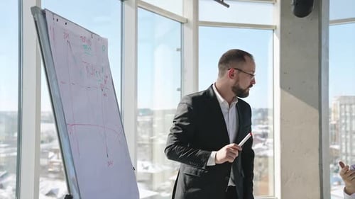 Business presentation in front of the teammates. Office team discussing the chart at the whiteboard.