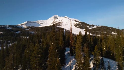 A drone shot of snowy Big Sky, Montana in winter, showcasing the ski resort and majestic mountain te