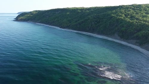 Beach Between a Ledge Covered with Vegetation and a Black Sea Under a Clear Blue Sky